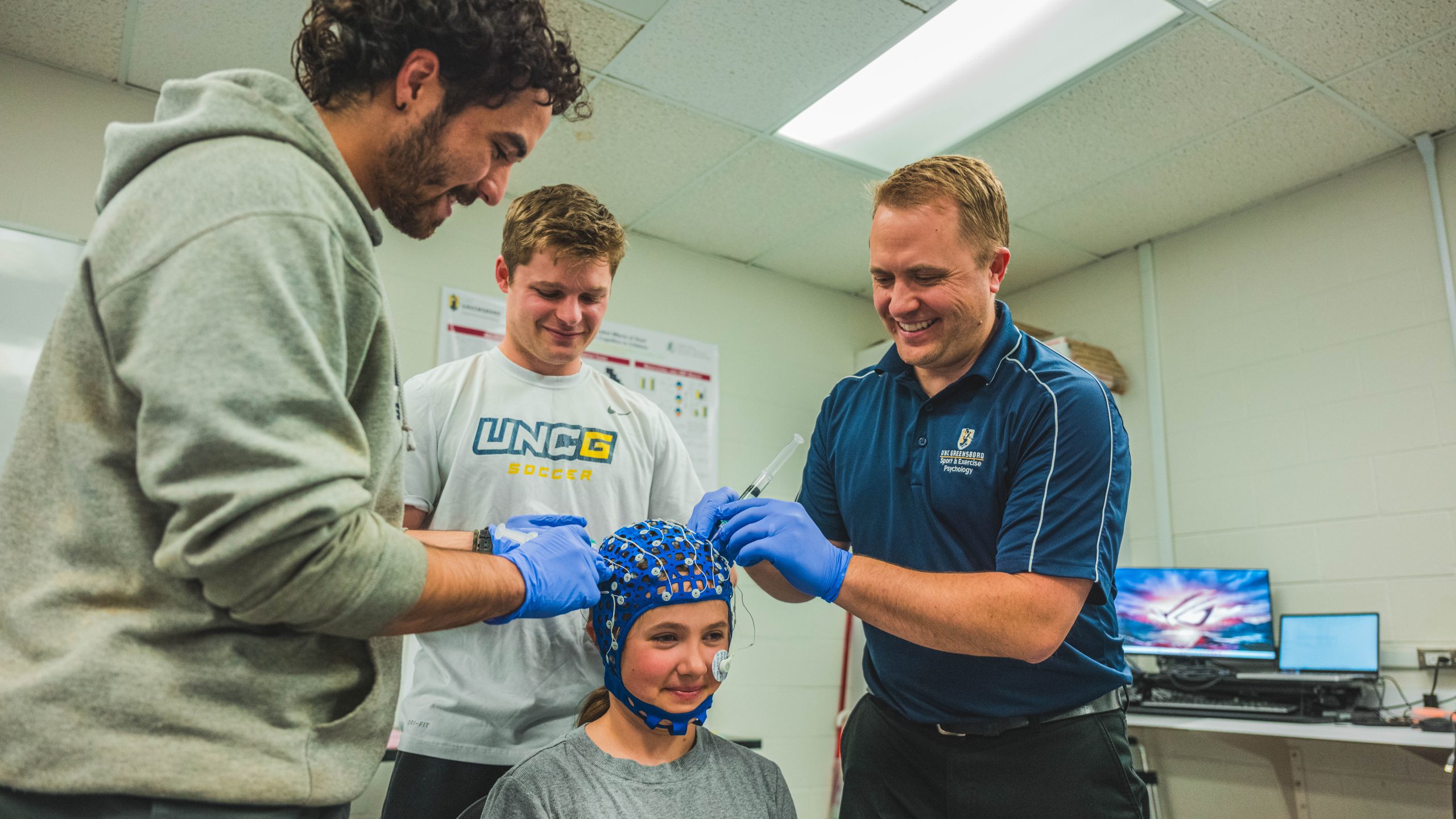 Three people put an EEG cap on a child.